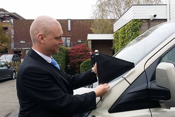 Facilitair medewerker Marcel Hessing illustreert de betekenis van de vlaggetjes op de overbrengauto