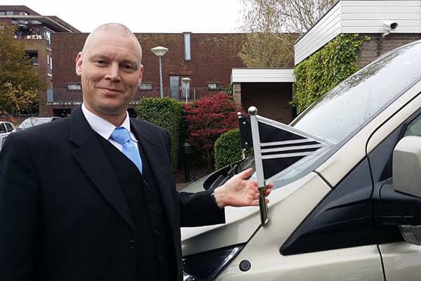 Facilitair medewerker Marcel Hessing illustreert de betekenis van de vlaggetjes op de overbrengauto